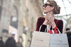 woman holding two white and beige shopping paper bags in building